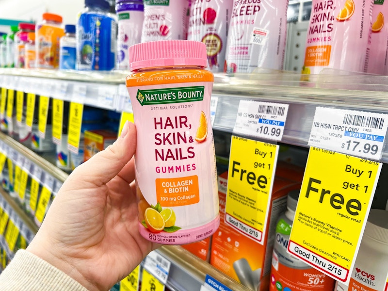 person holding a bottle of vitamins by a bogo free sign