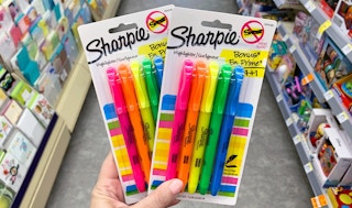 A hand holding Sharpie Highlighters in a store aisle.