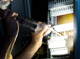 a person using a flashlight to fix an electrical box