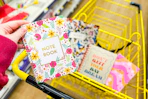 hand holding a journal above a yellow shopping cart full of journals