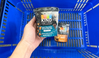pint of kind ice cream held up by left hand above blue walmart hand basket containing another pint of kind ice cream