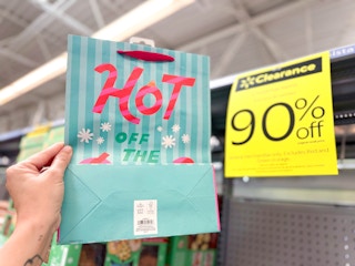 hand holding christmas gift bag in walmart aisle
