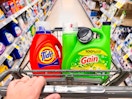 hand pushing a cart with Tide and Gain laundry detergents