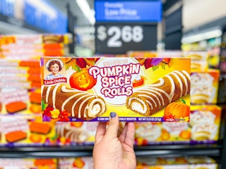 someone holding up a box of Little Debbie pumpkin spice rolls in Walmart