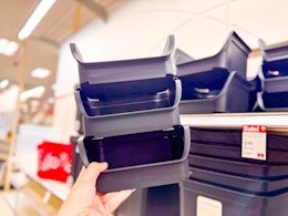 hand holding three black stackable storage bins stacked on top of each other