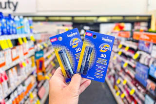 person holding 2 coppertone lip balms in an aisle