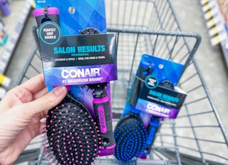 hand holding a set of conair hairbrushes in a cart