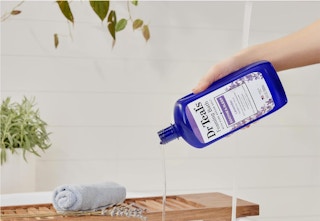 hand pouring foaming bath into water