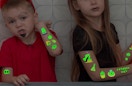 two kids with glow-in-the-dark temporary tattoos on their arms