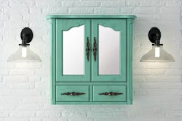 Lifestyle image of a vintage turquoise bathroom vanity mirror cabinet against a white brick wall w/ wall ligths