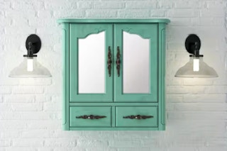 Lifestyle image of a vintage turquoise bathroom vanity mirror cabinet against a white brick wall w/ wall ligths