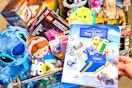 The 2025 Walmart toy shop catalog book being held in store next to a cart full of top toys. 