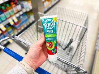 person holding toothpaste over a cart