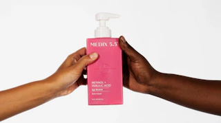 two hands holding a pink bottle of body lotion 