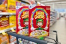 two boxes of lucky charms cereal balancing on shopping cart in store aisle