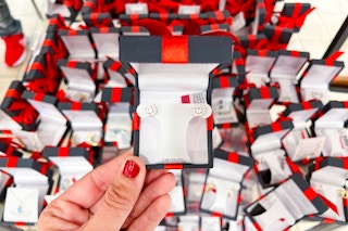 someone holding up a pair of earrings in a box 