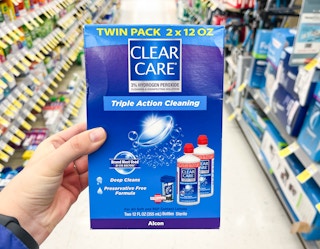 hand holding box of Clear Care Triple Action Cleaning Contact solution in aisle