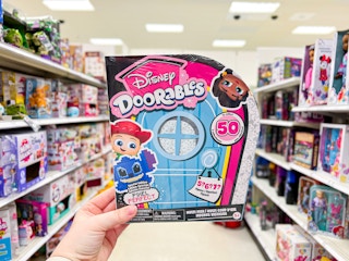 hand holding a disney doorables toy in a target aisle