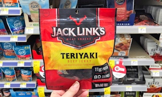 A hand holding Jack Link's beef jerky in a store aisle.