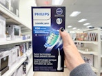 a hand holding a box with a picture of an electric toothbrush on it