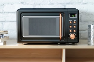 Lifestyle image of black & gold Costway Retro Microwave on countertop