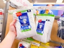 hand holding a pack of hanes kids' tees in front of a target shelf