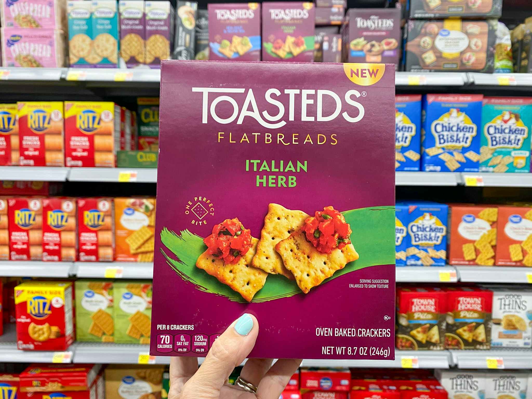 person holding a box of toasteds flatbreads crackers in an aisle