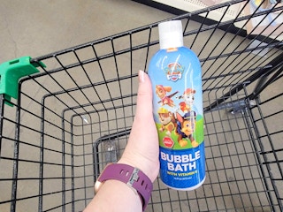 hand holding a bottle of paw patrol bubble bath over a cart