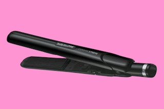 A black flat iron on a pink background