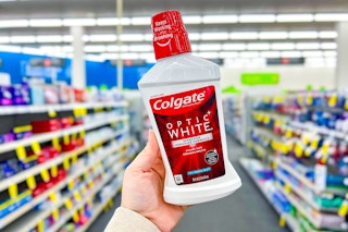person holding a bottle of colgate mouthwash in an aisle