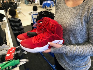 Woman holding Nike Air Jordan shoes inside Ross.
