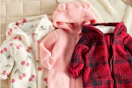 3 Carter's Baby Jumpsuits laid out on bed