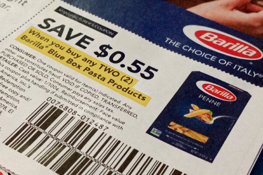 a close up on a manufacturer coupon for Barilla that says " Save 55 cents when you buy any TWO Barilla Blue Box Pasta Products" that is h...