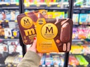 hand holding two magnum caramel ice cream bars in walmart frozen aisle