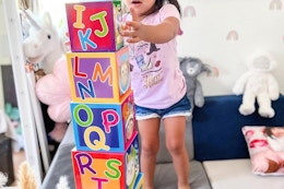 a kid playing with giant cubes