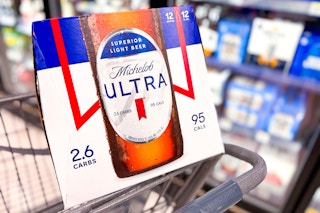 pack of beer sitting in shopping cart in store beer aisle
