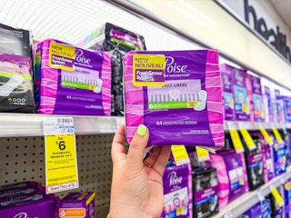 person holding poise pads by the shelf