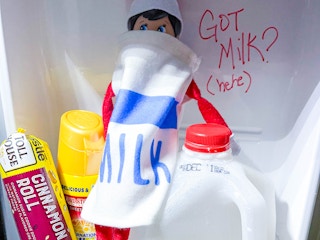 an elf on the shelf doll dressed like milk in a fridge drawer 
