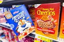 hand holding box of frosted flakes next to honey nut cheerios