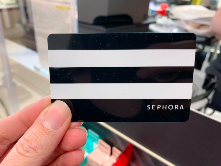 A person holding up a Sephora gift card