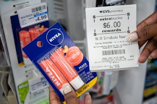 A woman holding CVS Extrabucks rewards for $6 next to Nivea lip balm next to a price tag that says, $4.99.