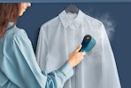 woman using steamer on dress shirt
