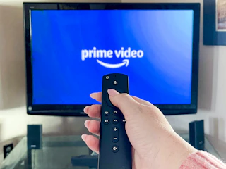 person pointing a remote at a tv with amazon prime video app launching