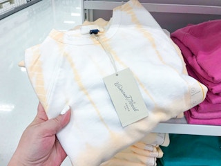 hand grabbing women's sweatshirt off display shelf at Target