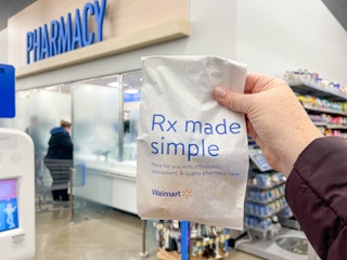 a person holding a refill bag in front of the walmart pharmacy