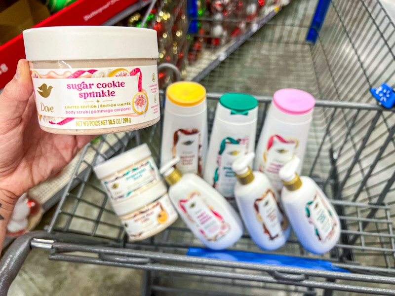 hand holding body scrub over walmart cart filled with dove holiday treats body and hand wash and scrub