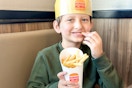 a young boy eating fries at burger king