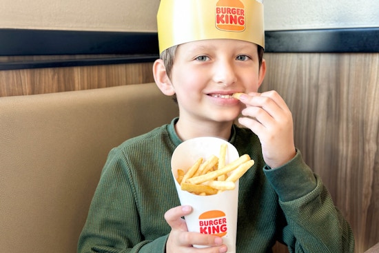 a young boy eating fries at burger king