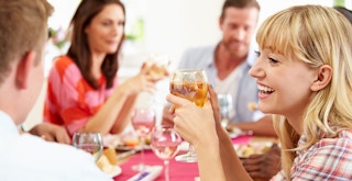 friends gathered around table laughing and drinking wine