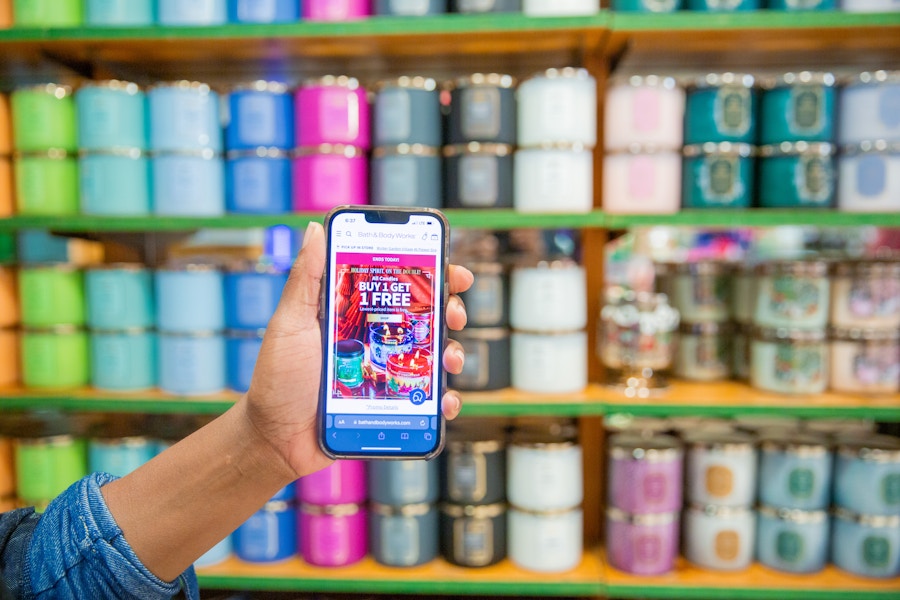 Person holding up phone next to candle display at bath and body works